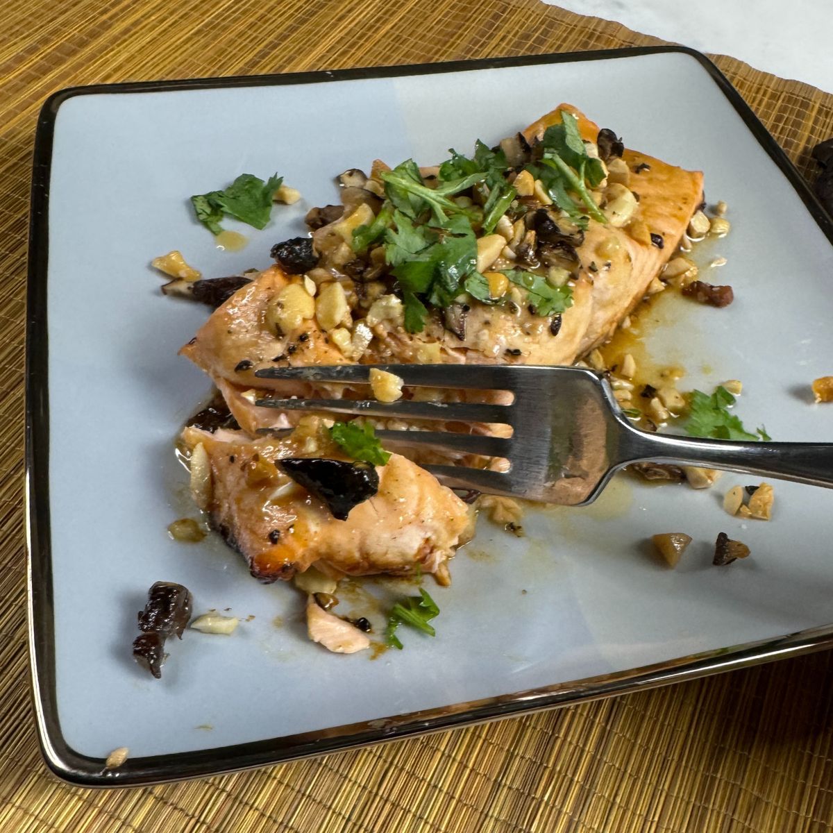 Cutting into glazed salmon with mushrooms and cashews