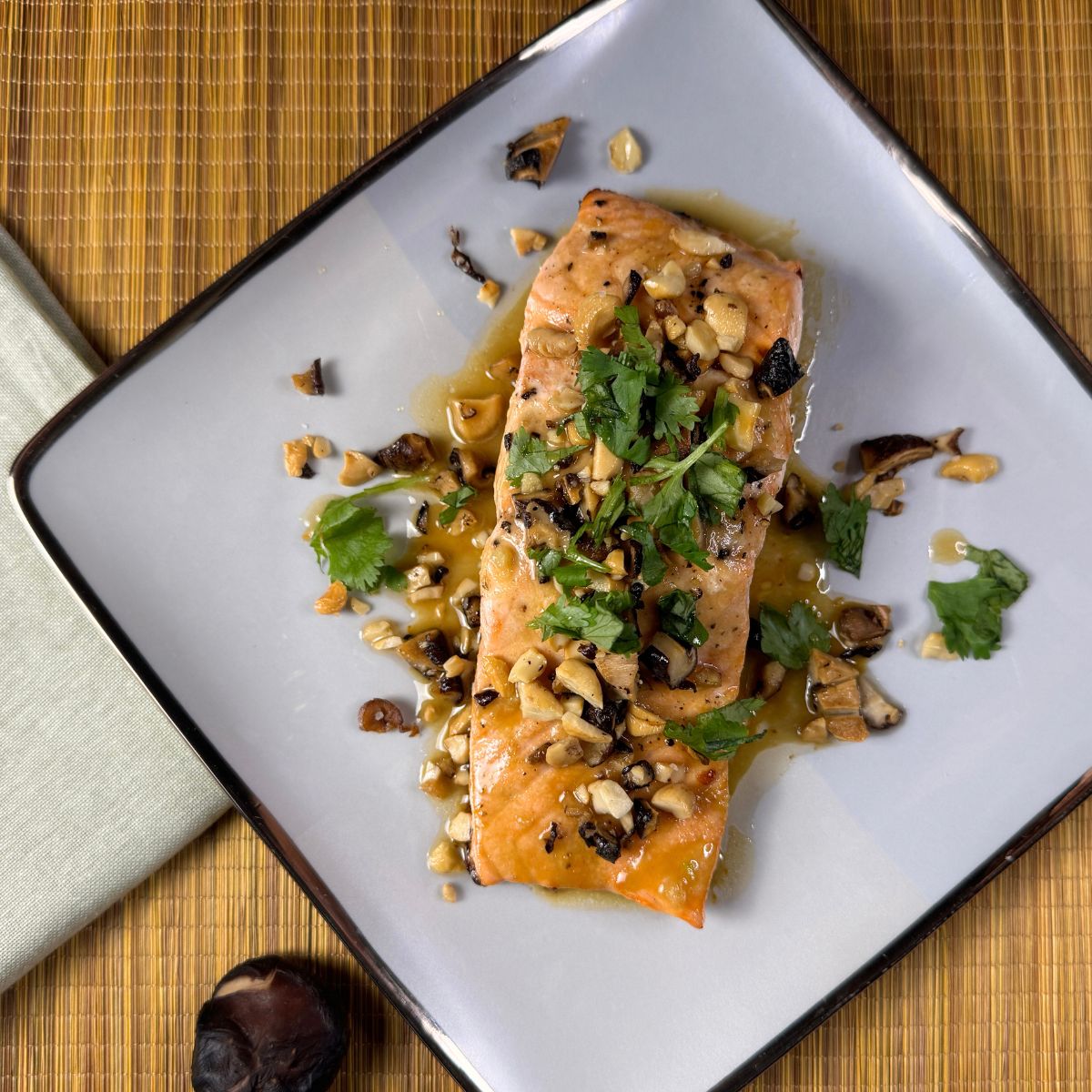 Asian Glazed Salmon plated with mushroom cashew topping and chopped cilantro